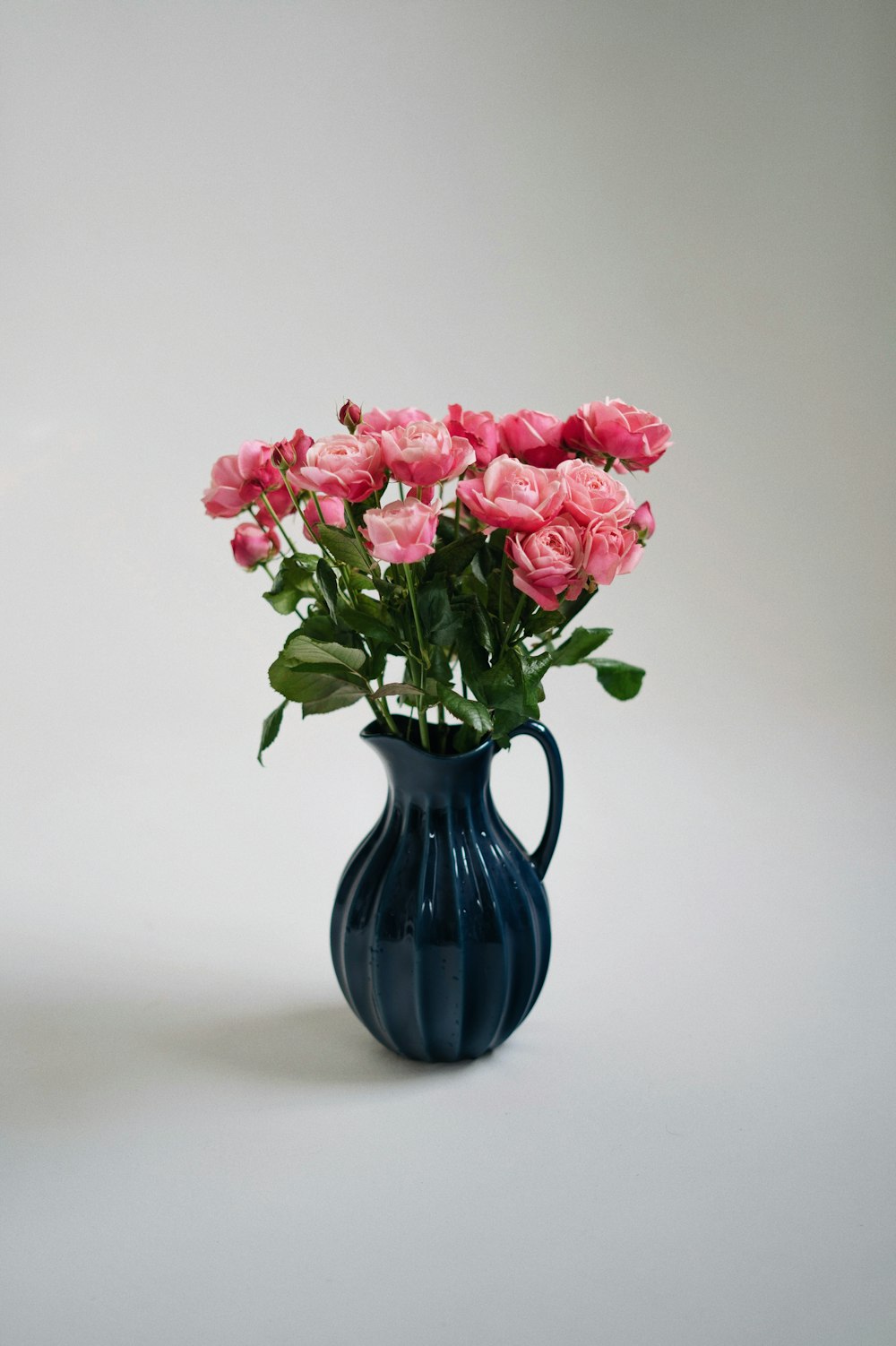 a blue vase with pink roses in it