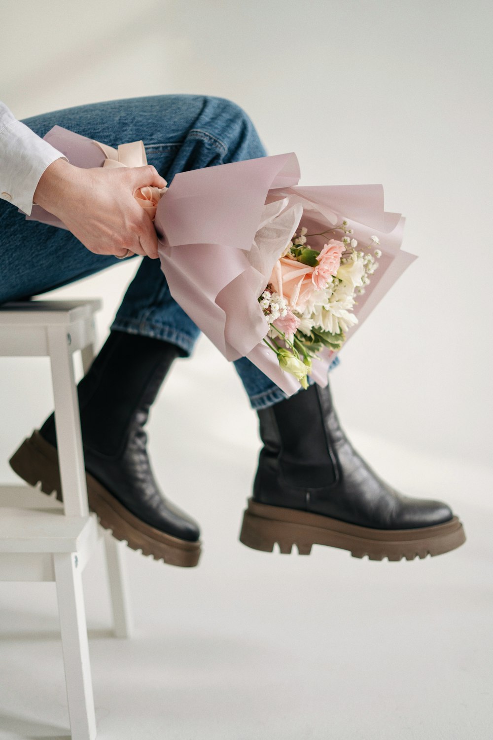 a person sitting on a stool holding a bouquet of flowers