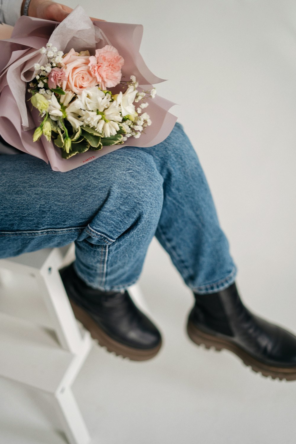 a person sitting on a stool holding a bouquet of flowers