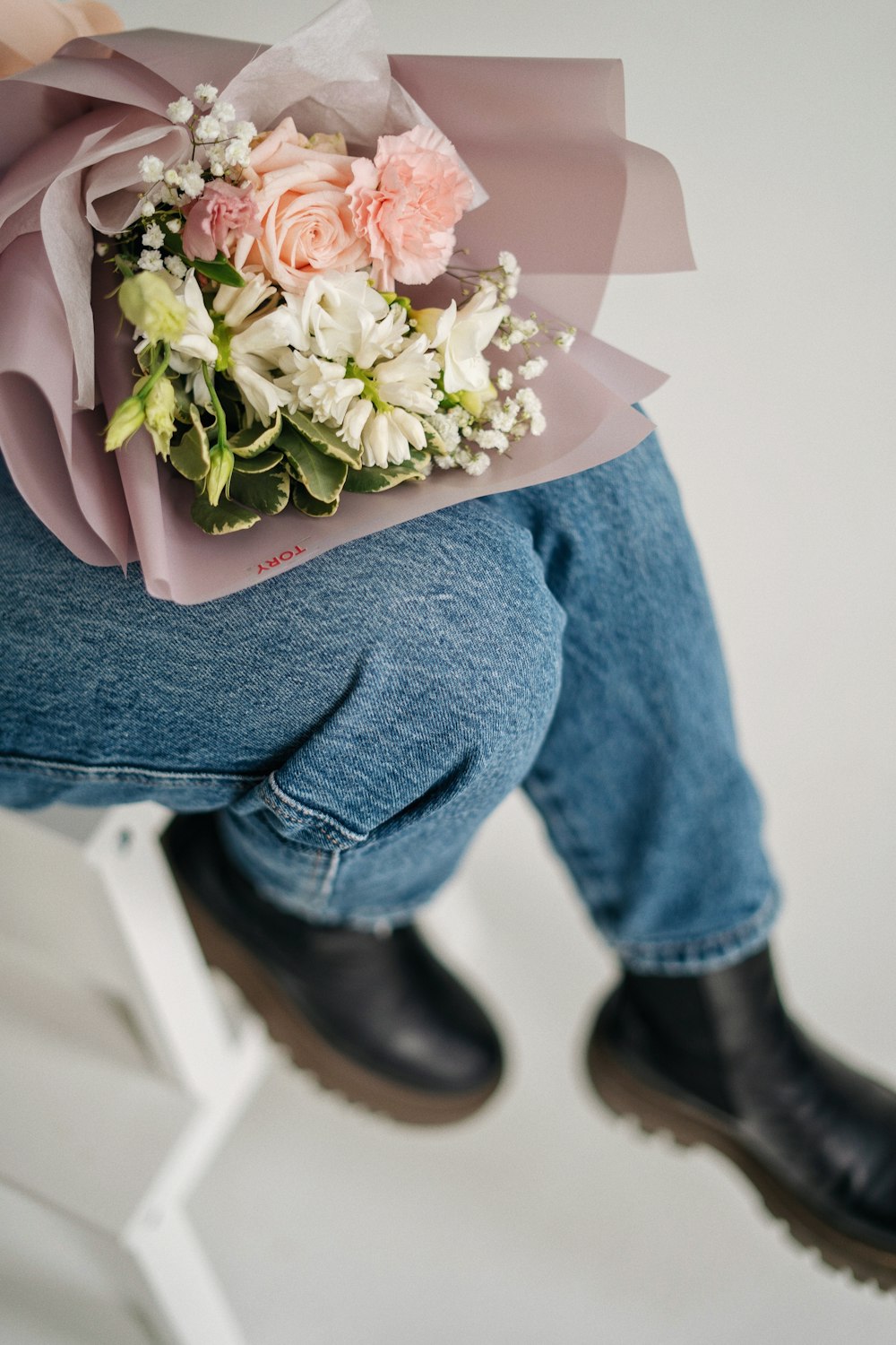 a person sitting on a stool holding a bouquet of flowers