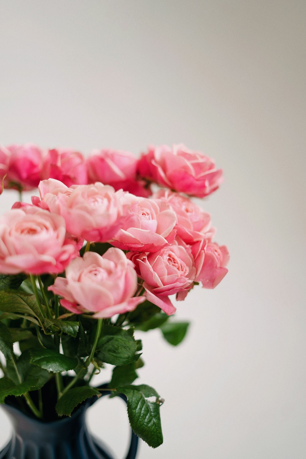 a blue vase filled with pink roses on top of a table