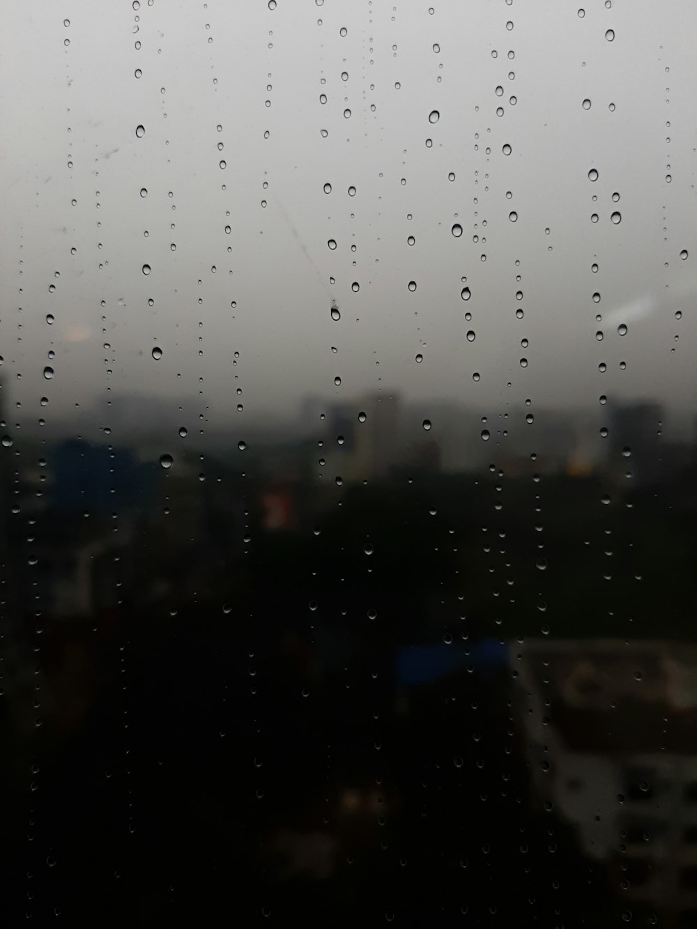 rain drops on a window with a city in the background