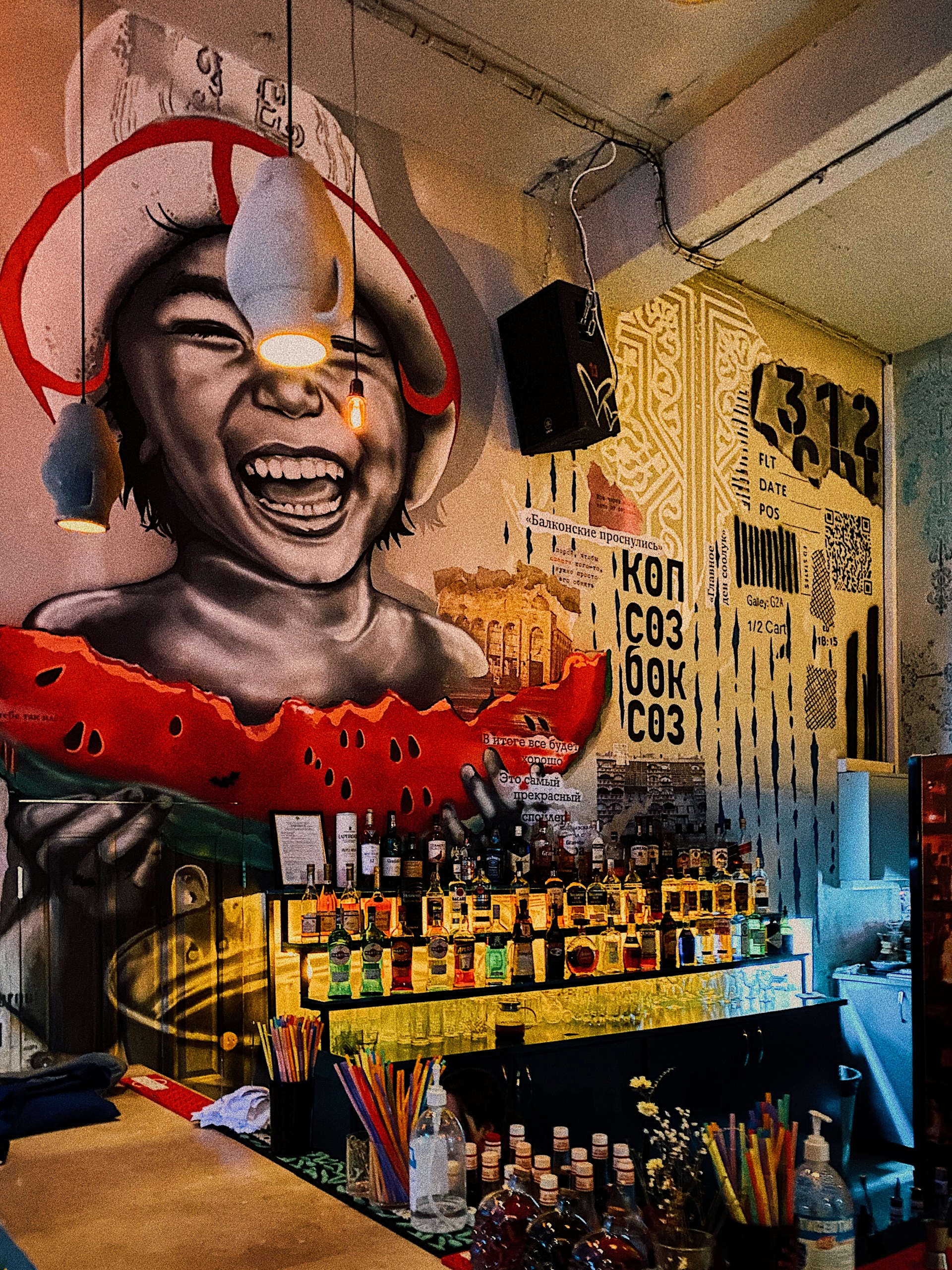 Vibrant mural wall inside Post Street Bar, bursting with neon graffiti colors and layered stencil art under moody charcoal lighting.