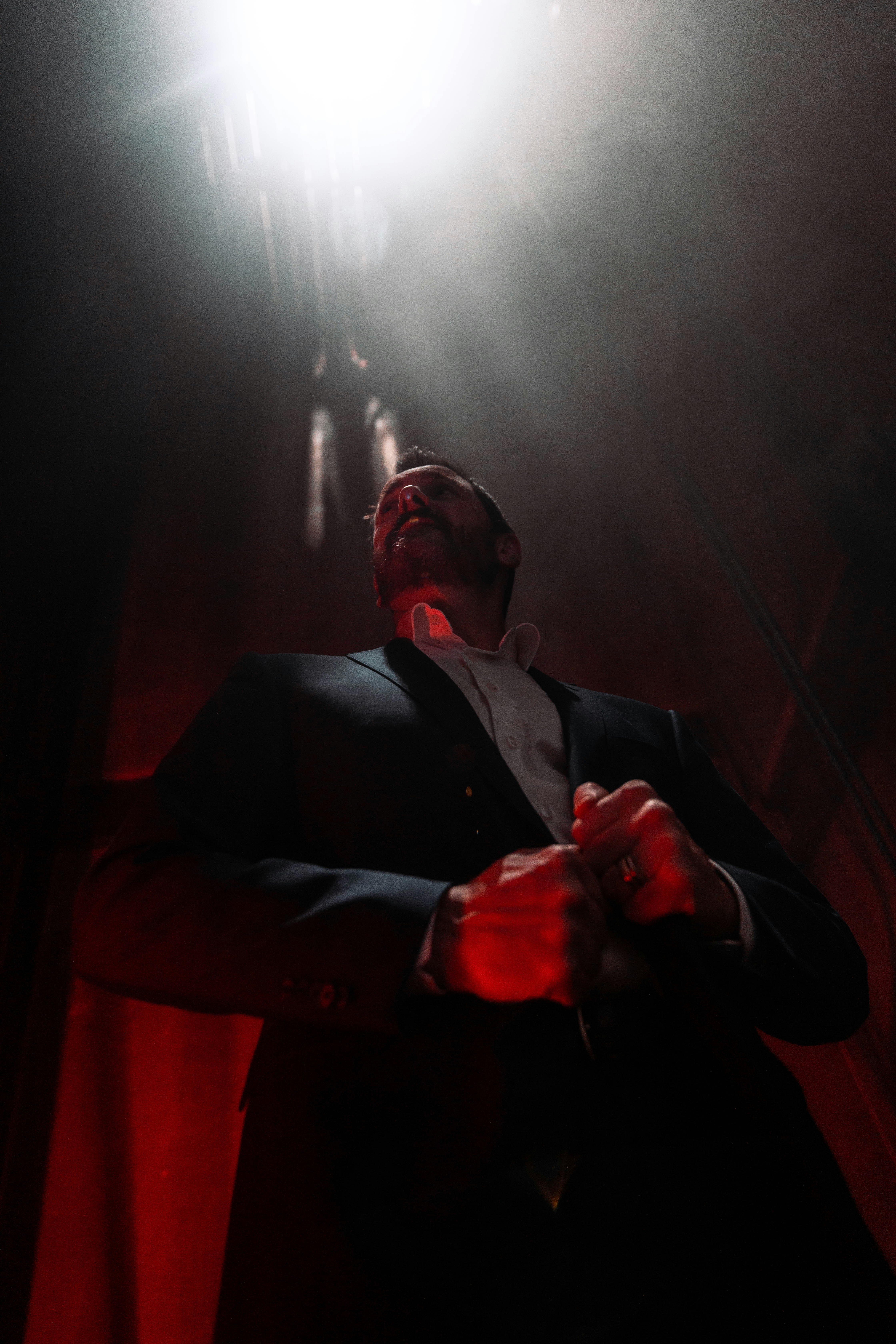 Ein Mann in Anzug und Krawatte steht in einem dunklen Raum
