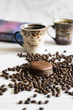 a table topped with two cups of coffee next to a pile of coffee beans