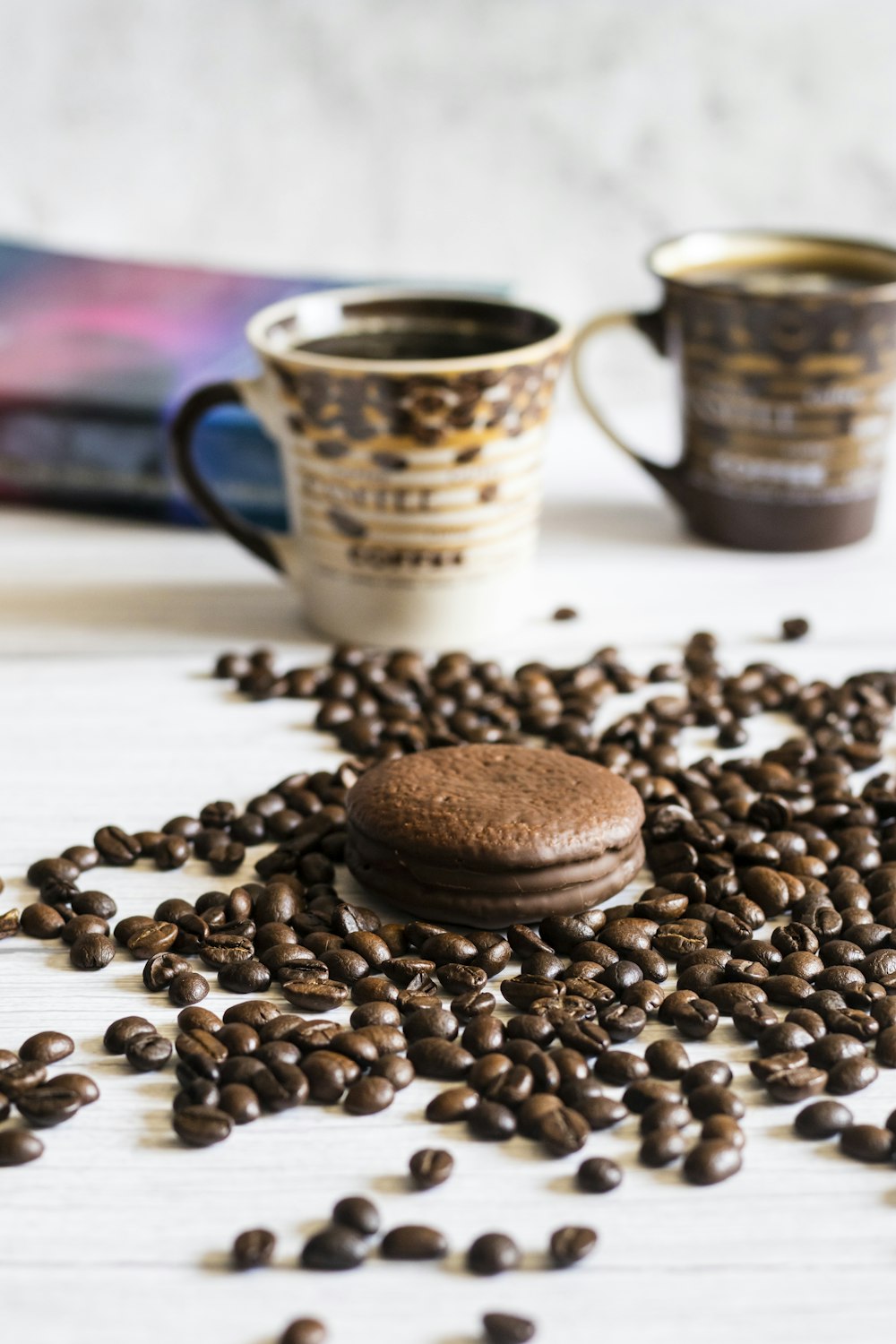 a table topped with two cups of coffee next to a pile of coffee beans