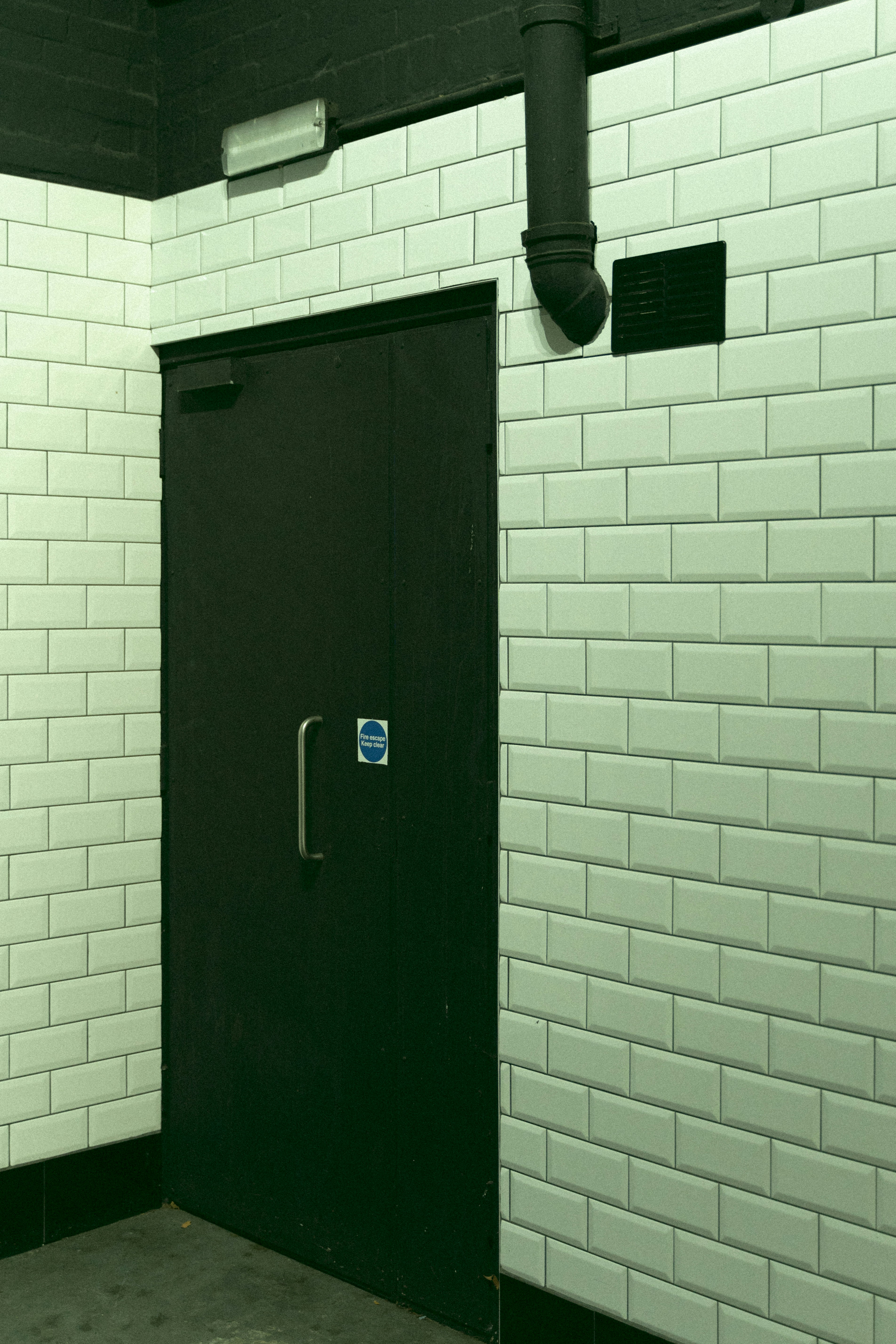 a black door in a white brick wall