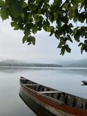 A day boat moored at a wooden pier framed by lush greenery and calm lake waters.