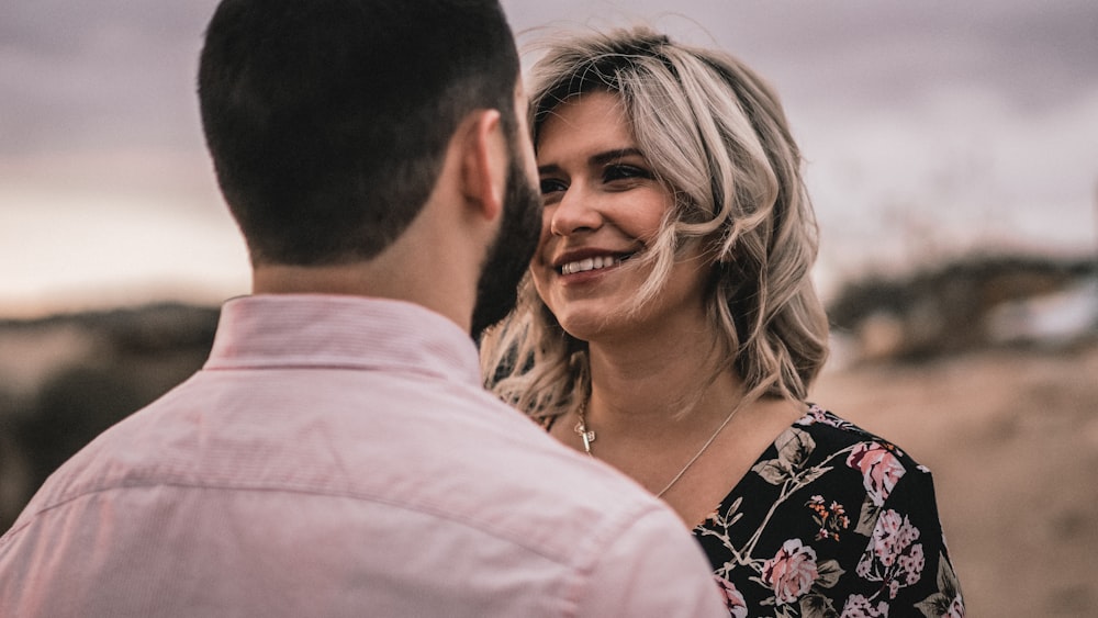 a man standing next to a woman in a floral dress