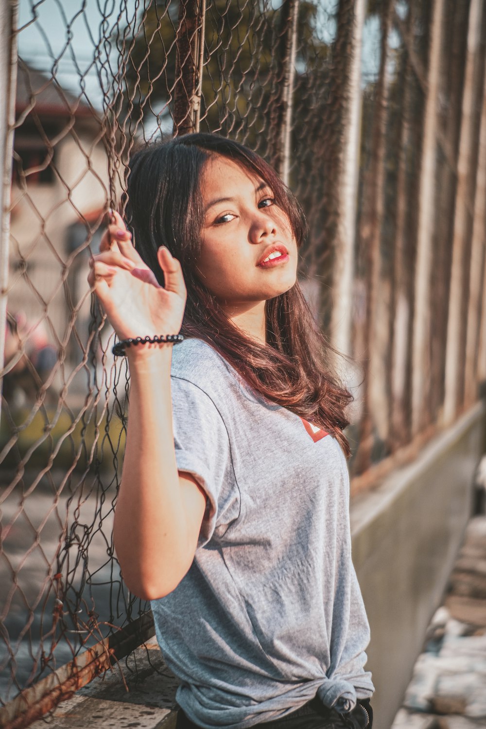 a woman leaning against a fence and looking up