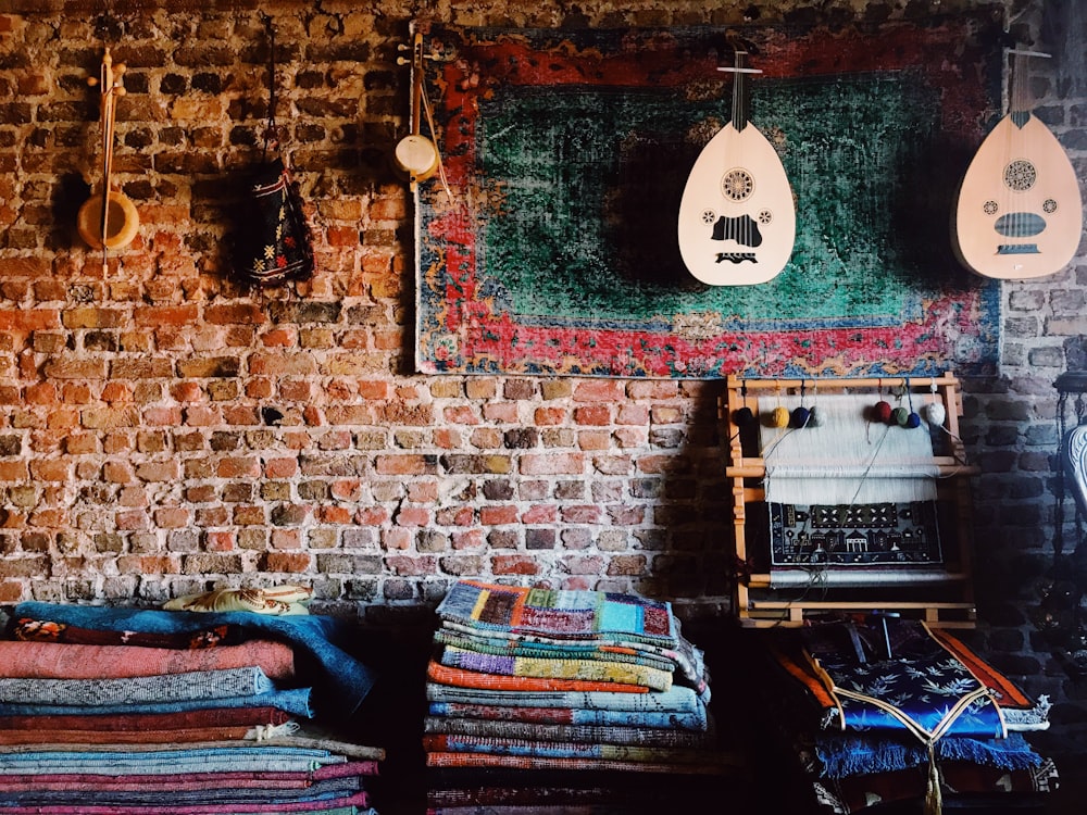 a room with a brick wall and various rugs