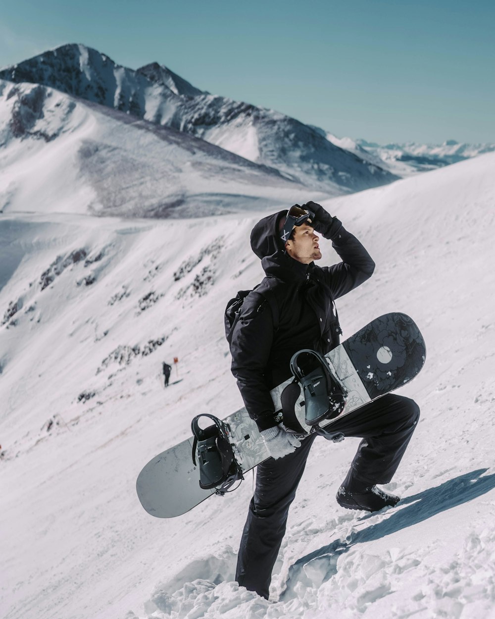 a man holding a snowboard on top of a snow covered slope