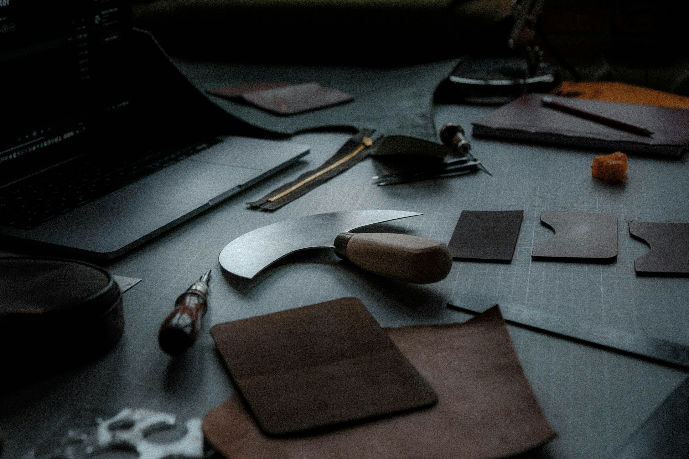 Leather working tools on a dark workbench