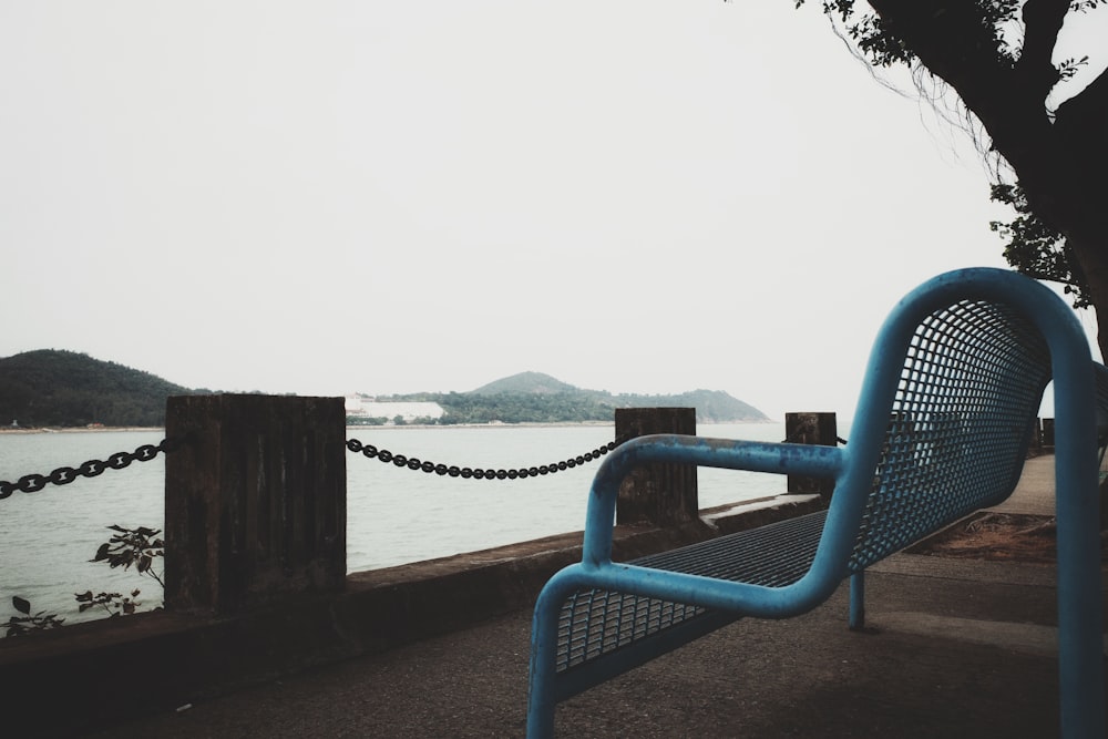 a blue bench sitting next to a body of water