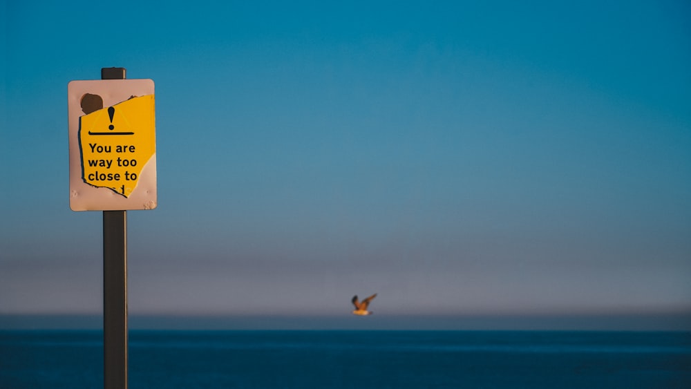 a yellow and white sign sitting on the side of a road