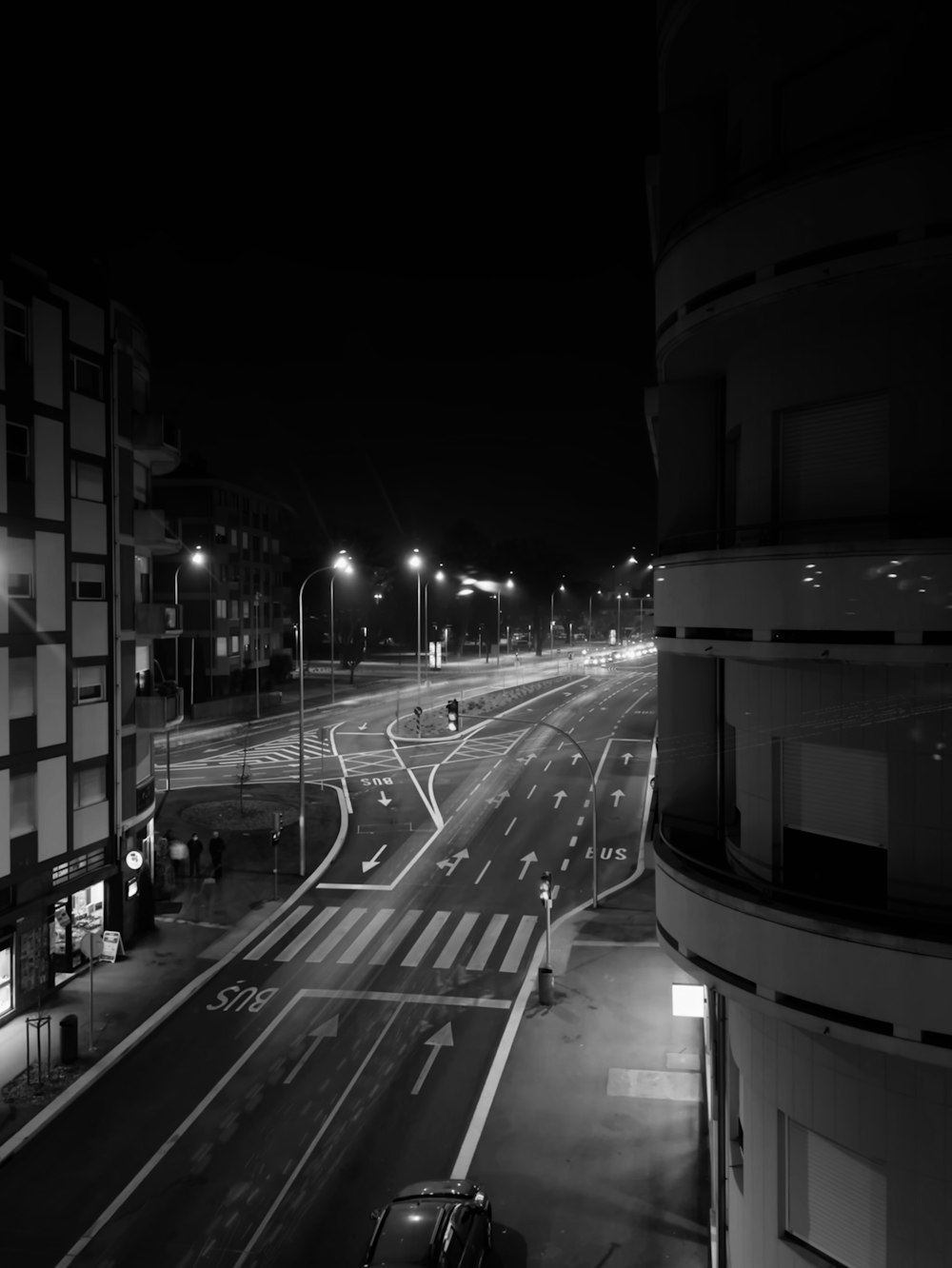 a black and white photo of a street at night