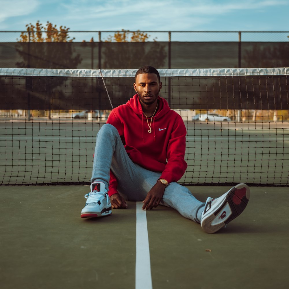 a man sitting on a tennis court next to a net