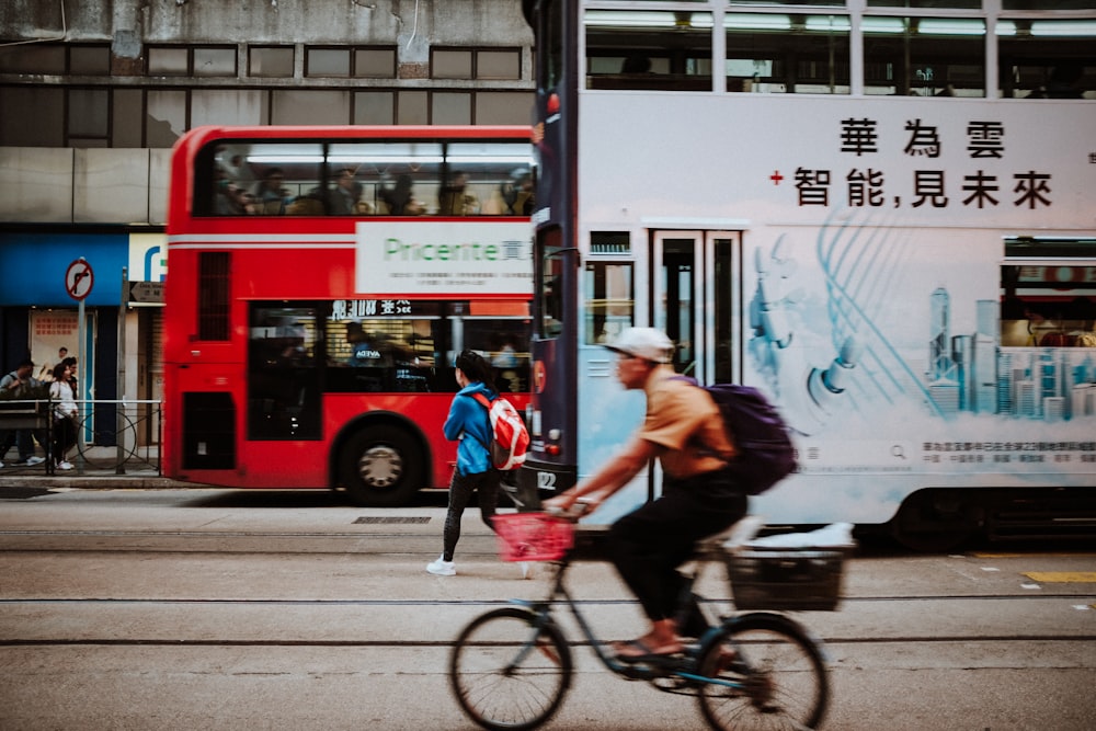 a man riding a bike down a street next to a bus