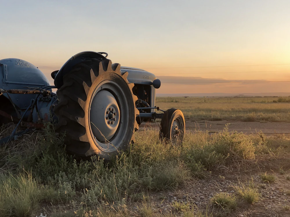Vintage tractor parked in a field at sunset