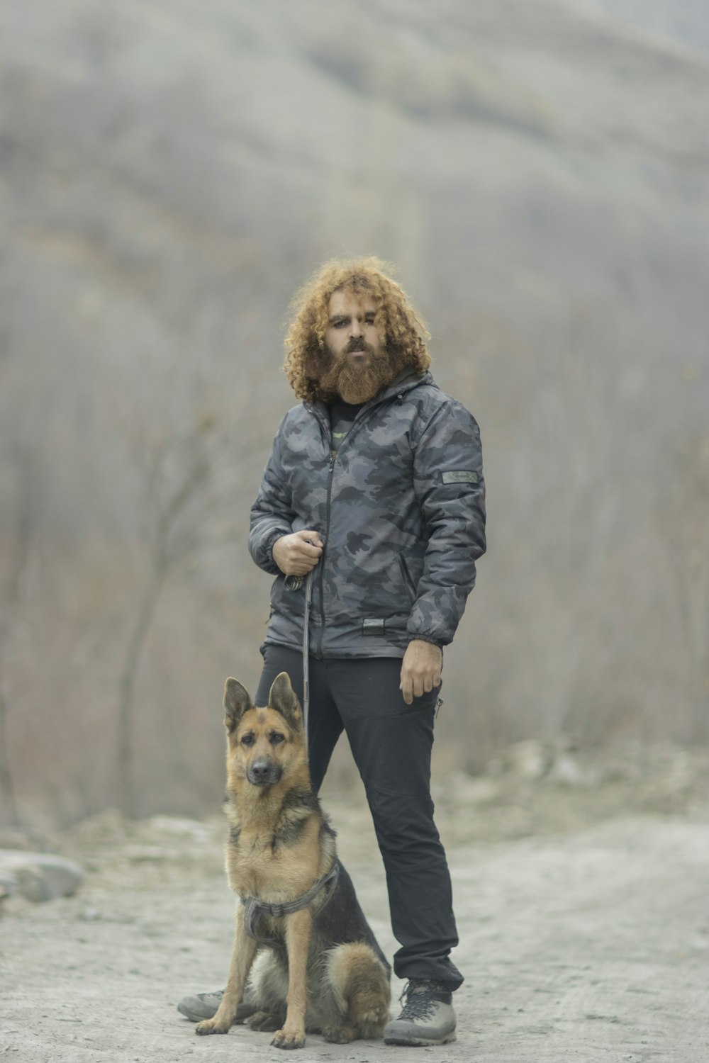 a man with a beard standing next to a dog