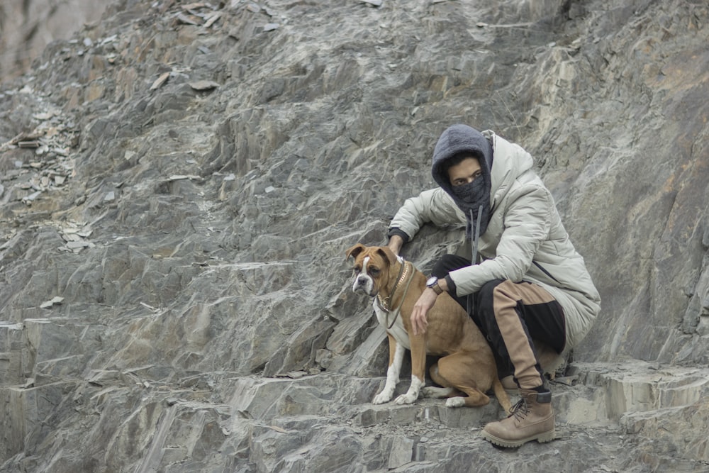 a person sitting on a rock with a dog