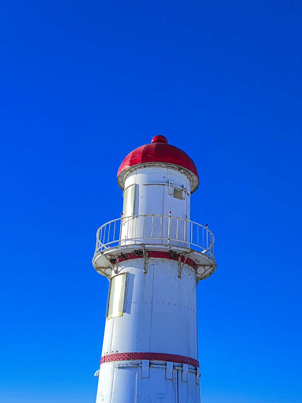 a white lighthouse with a red top on a clear day