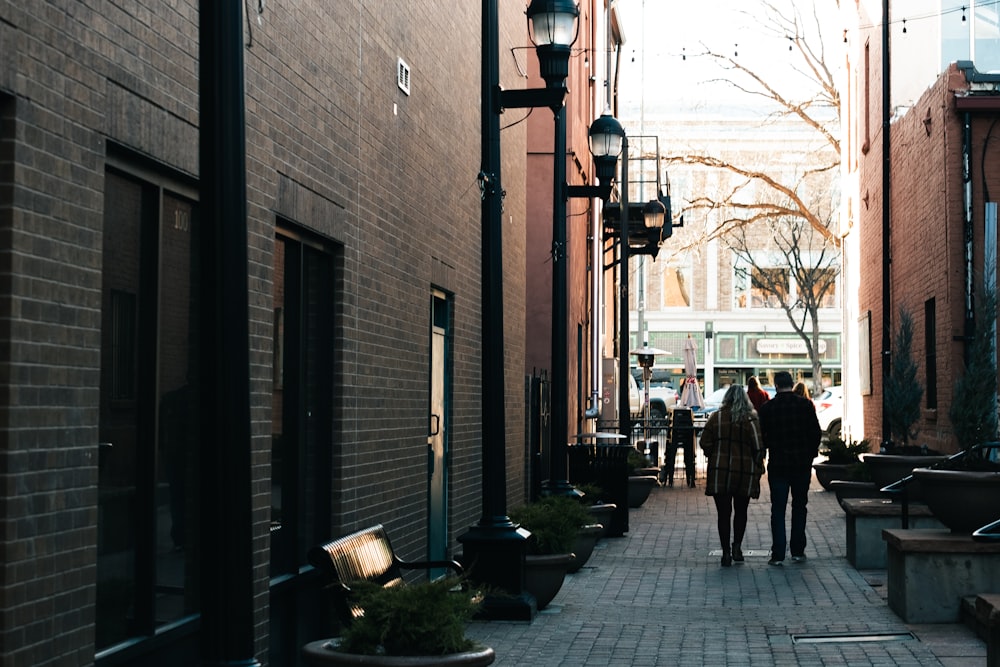 a couple of people walking down a street next to tall buildings