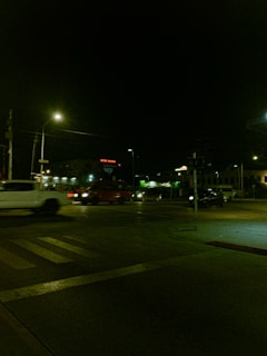 A night-time street scene featuring a dimly lit intersection with vehicles in motion. Streetlights cast a yellowish glow over the road, and a building with the sign 'Hotel Yucatan' is visible in the background.