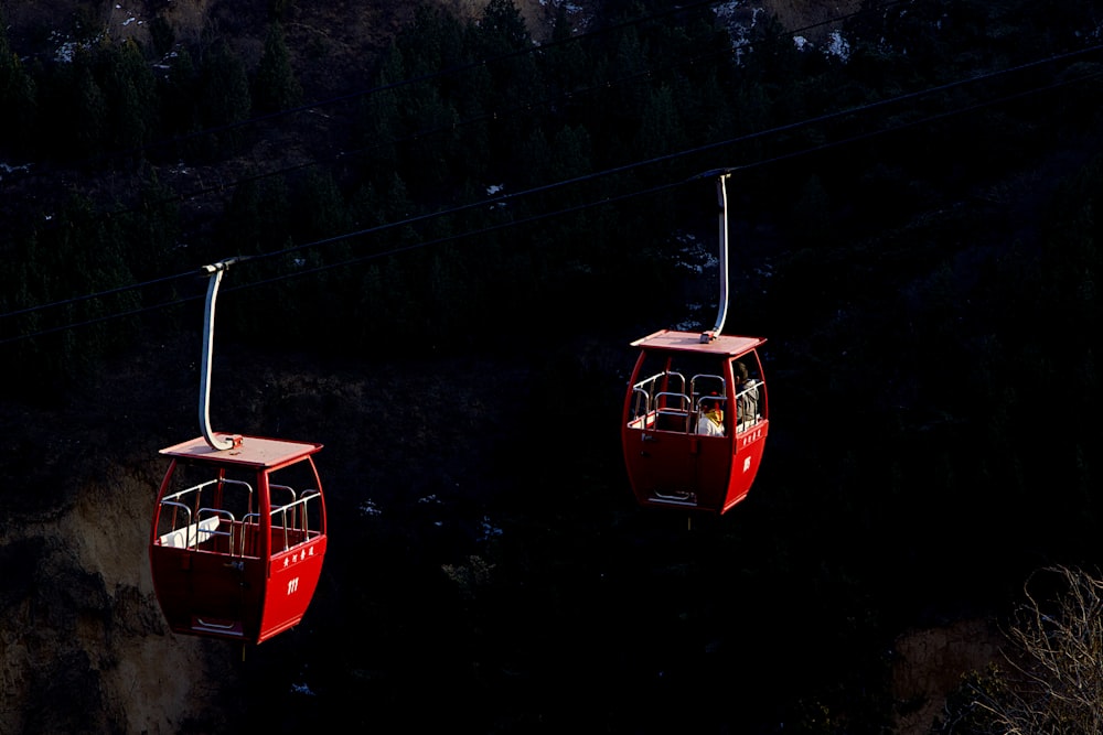 a couple of red gondolas hanging from a wire
