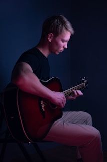 a man sitting in a chair playing a guitar