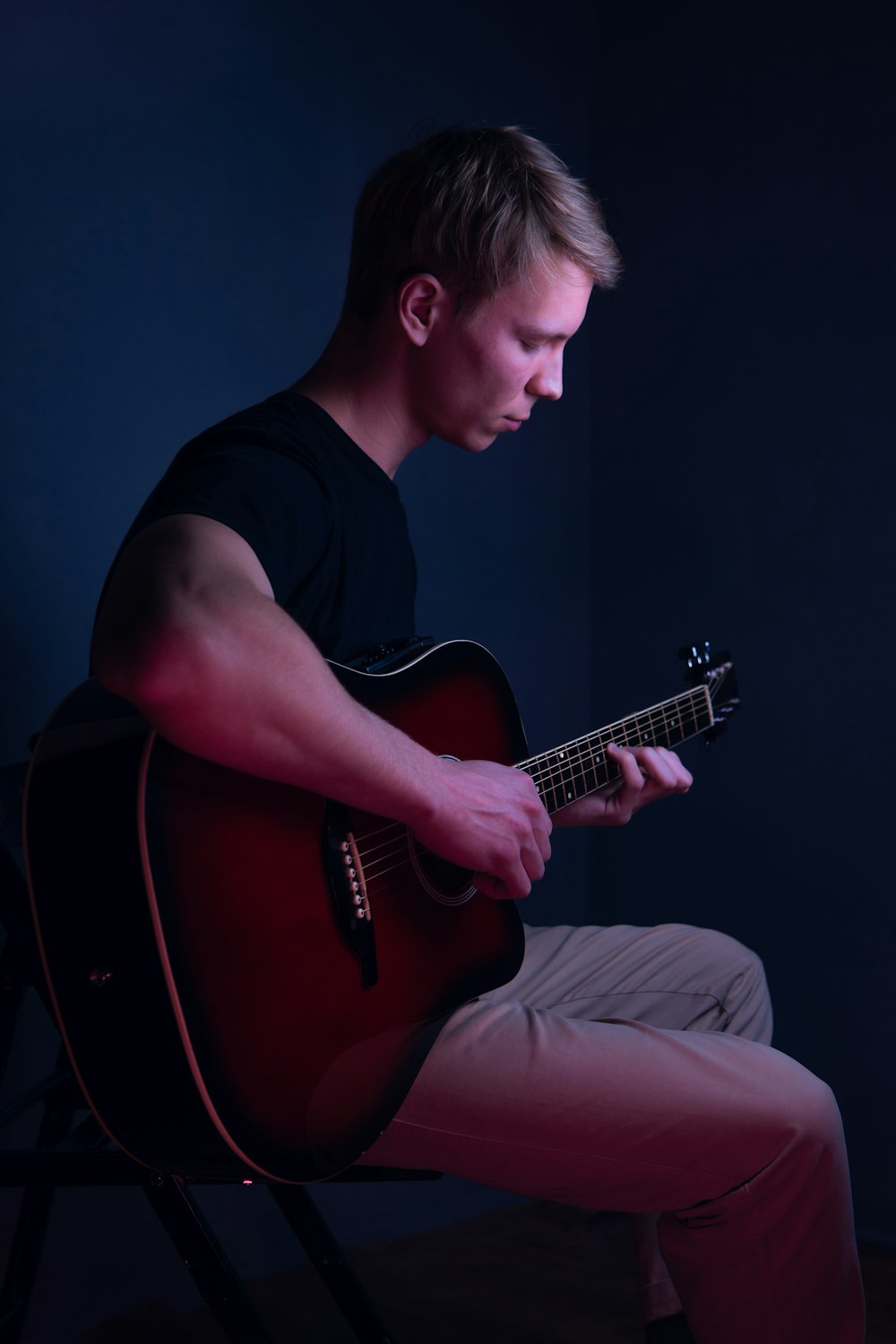 a man sitting in a chair playing a guitar