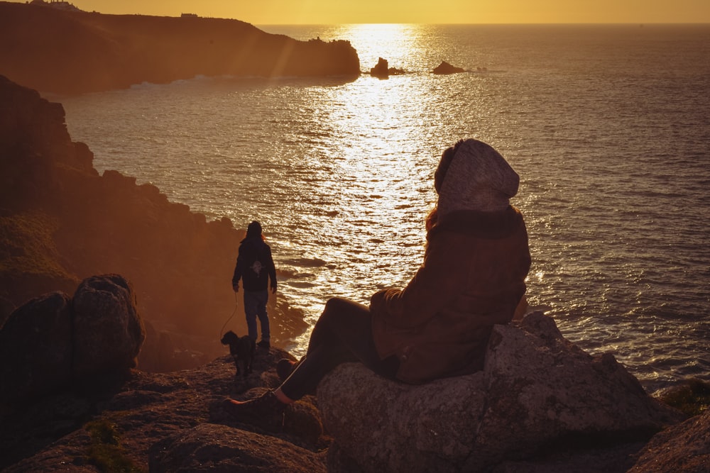 Un hombre y un perro parados en un acantilado con vistas al océano