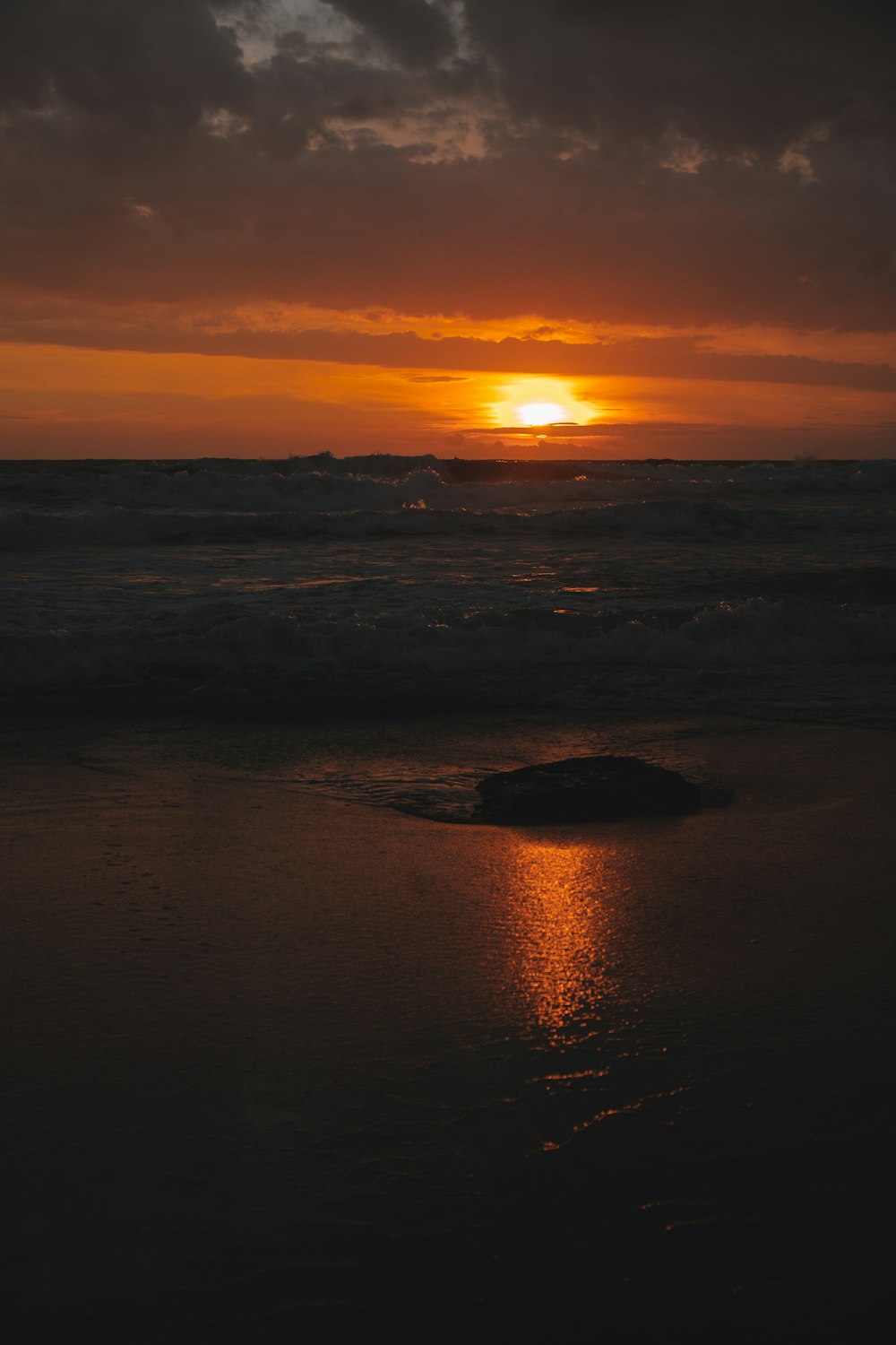 the sun is setting over the ocean on a cloudy day