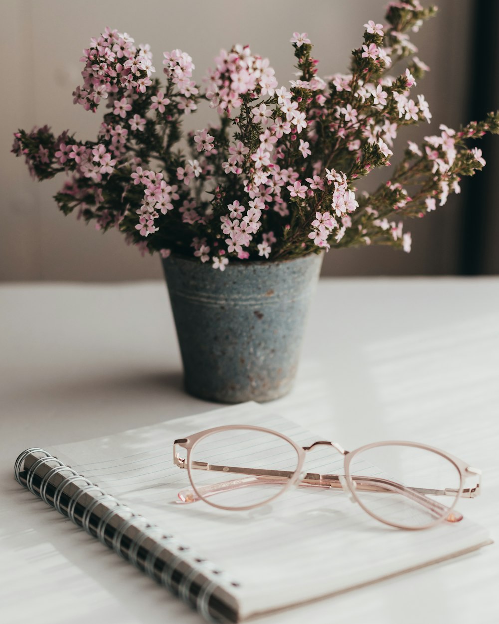 a notebook, glasses, and flowers on a table