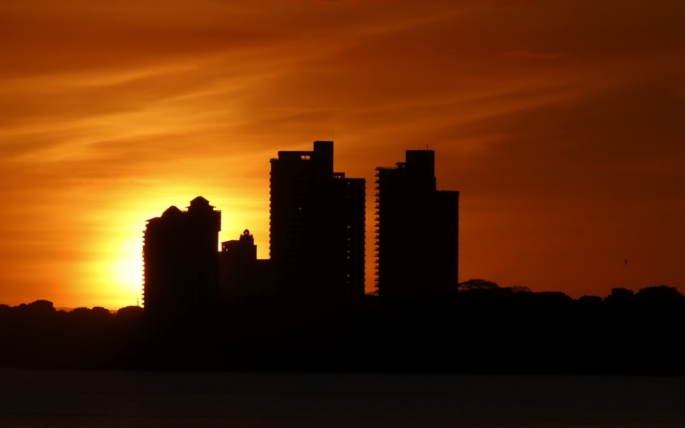 the sun is setting over a city with tall buildings