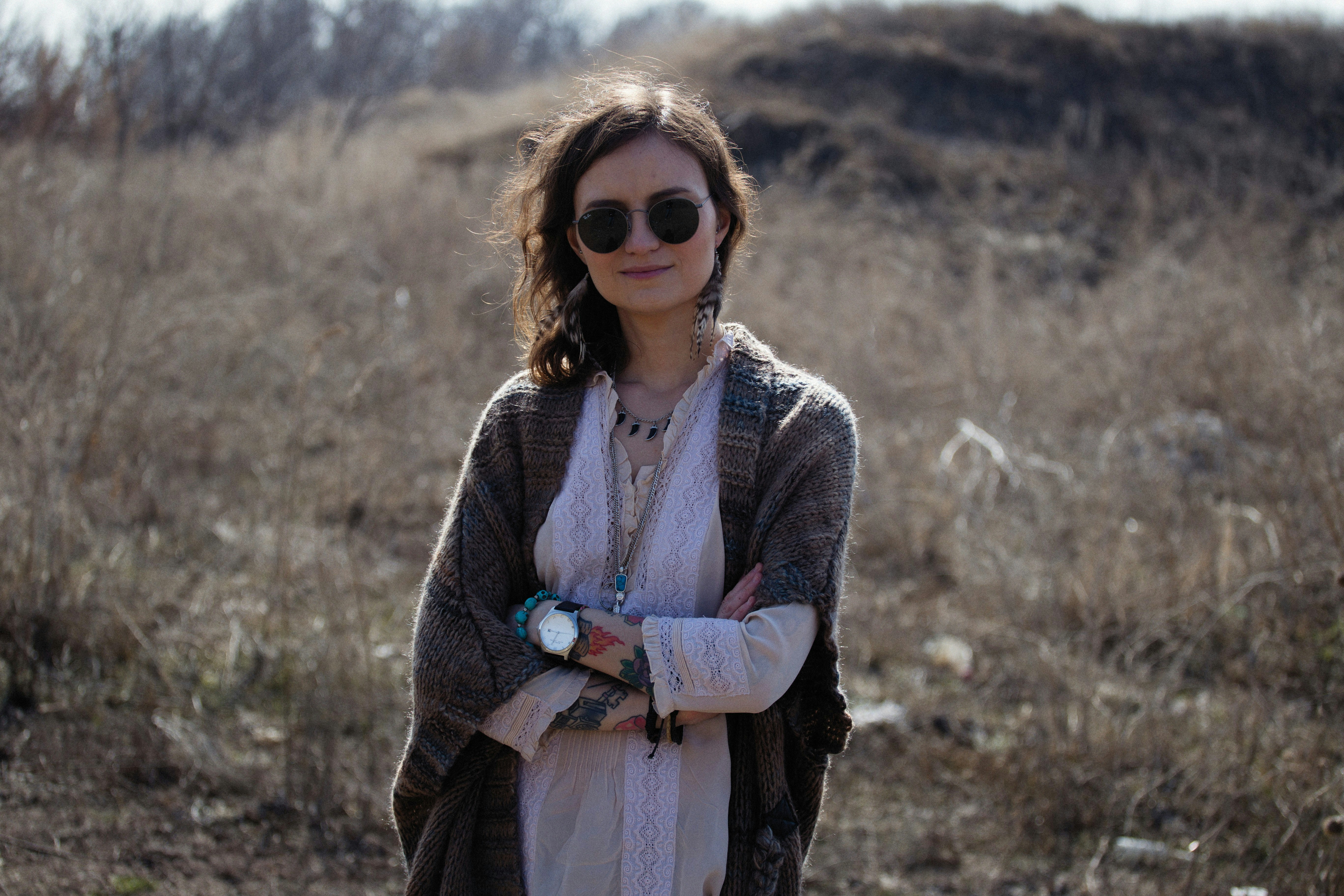 a woman standing in a field with her arms crossed