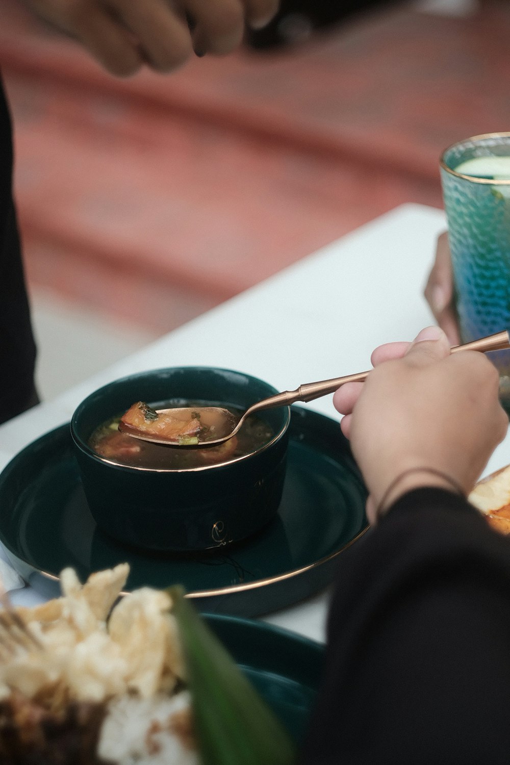 a person eating a bowl of soup with a spoon