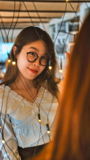 A candid, tasteful shot of a college girl in a cozy dorm room setting, smiling softly while sitting comfortably.