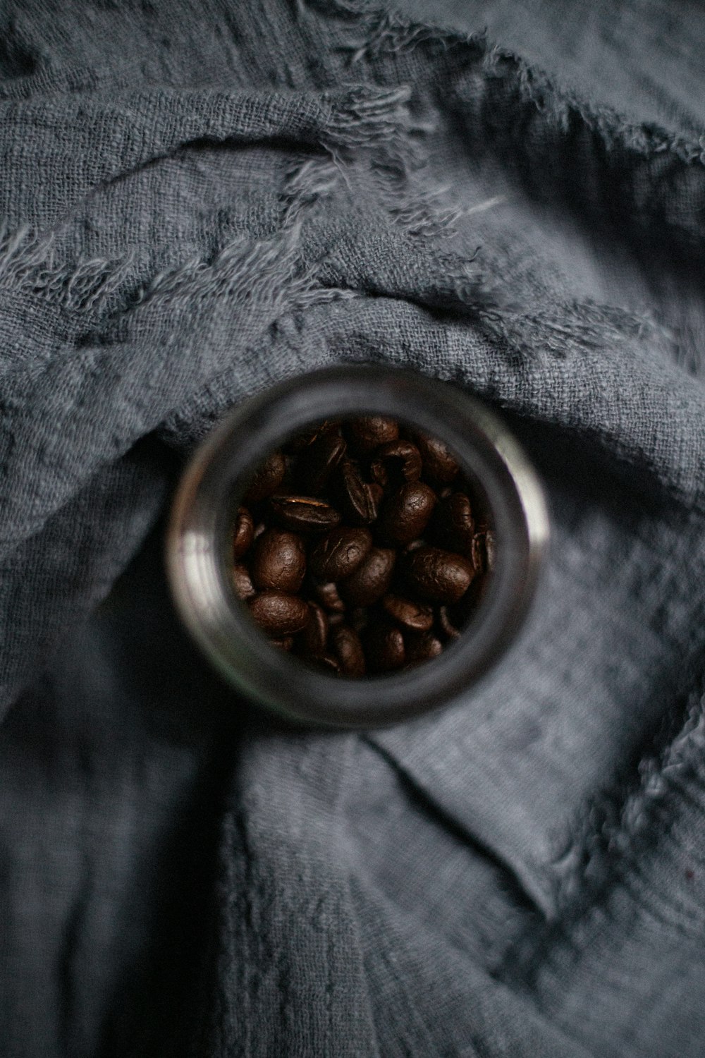 a glass jar filled with coffee beans on top of a gray cloth