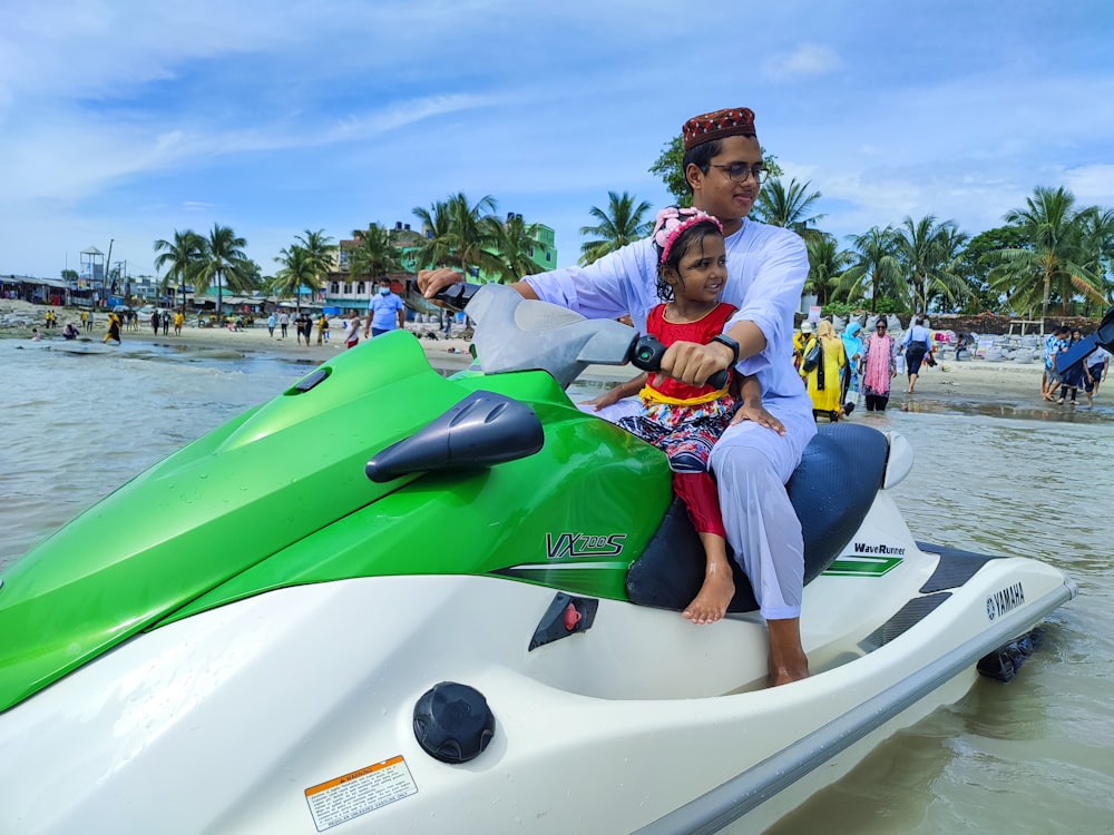 a man and a little girl riding on a green and white jet ski