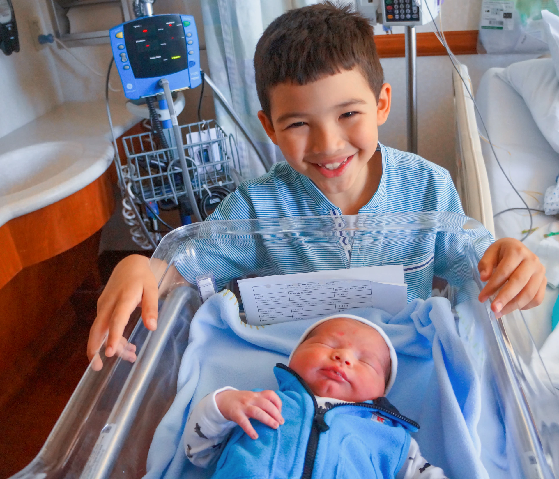 a young boy holding a baby in a hospital bed