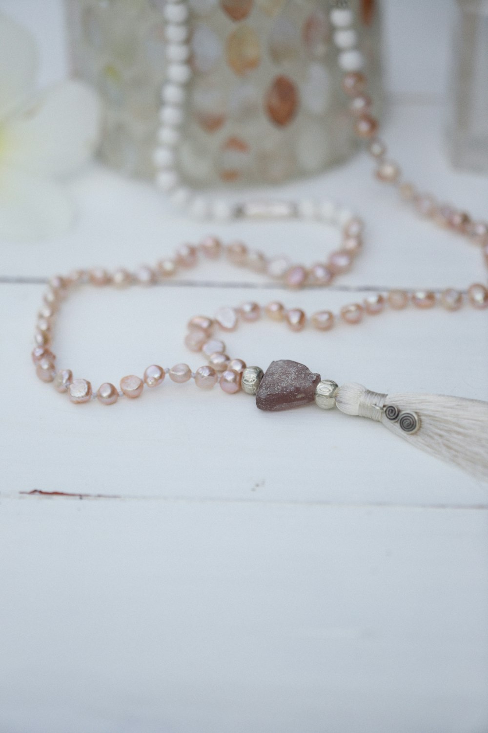 a necklace with a tassel on a white table