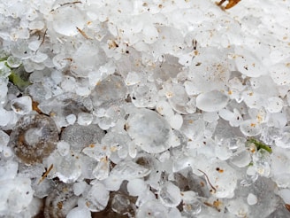 A close-up of hailstones scattered on a damaged roof, highlighting the impact of severe weather.