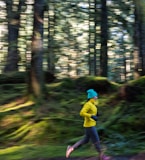 a person running in the woods with trees in the background