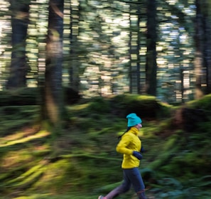 a person running in the woods with trees in the background