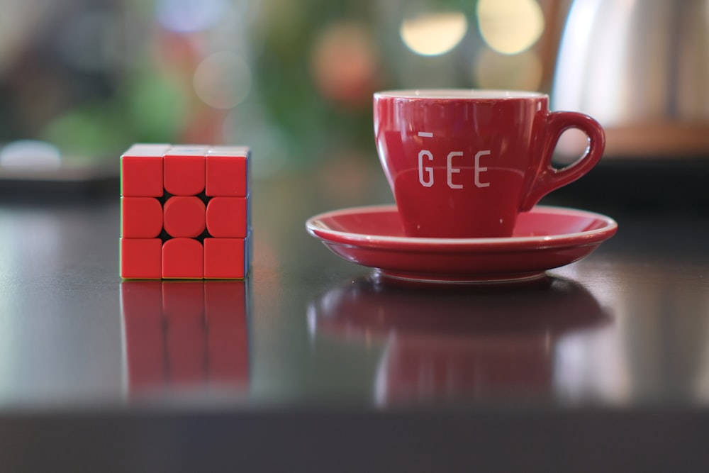 a red cup and saucer sitting on top of a table