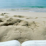 A tranquil beach scene with a tablet open to budgeting graphs and a passport lying nearby.