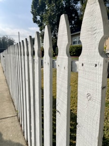 A friendly Affordable Fence Co team member installing a wooden fence on a sunny day in a Houston neighborhood.