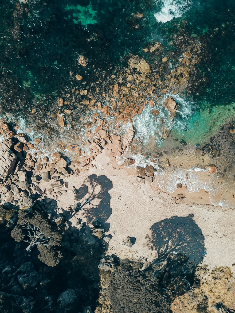 an aerial view of a beach with rocks and water