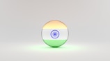 A 3D sphere with the Indian flag design, featuring horizontal stripes of saffron, white with a blue Ashoka Chakra at the center, and green. The sphere is set against a light, neutral background.